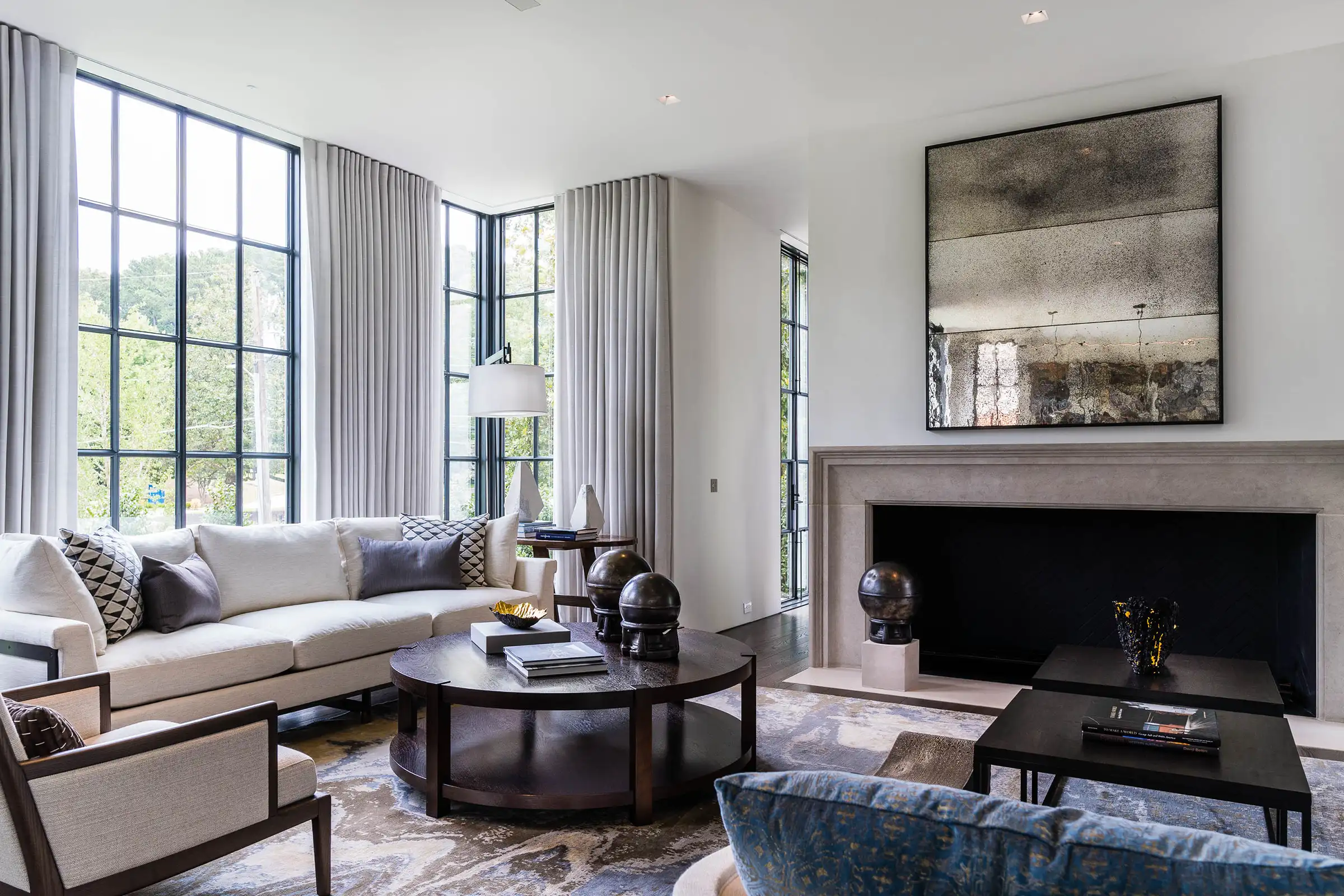 Living room with steel-framed windows, drapery and a stone fireplace in an Atlanta home