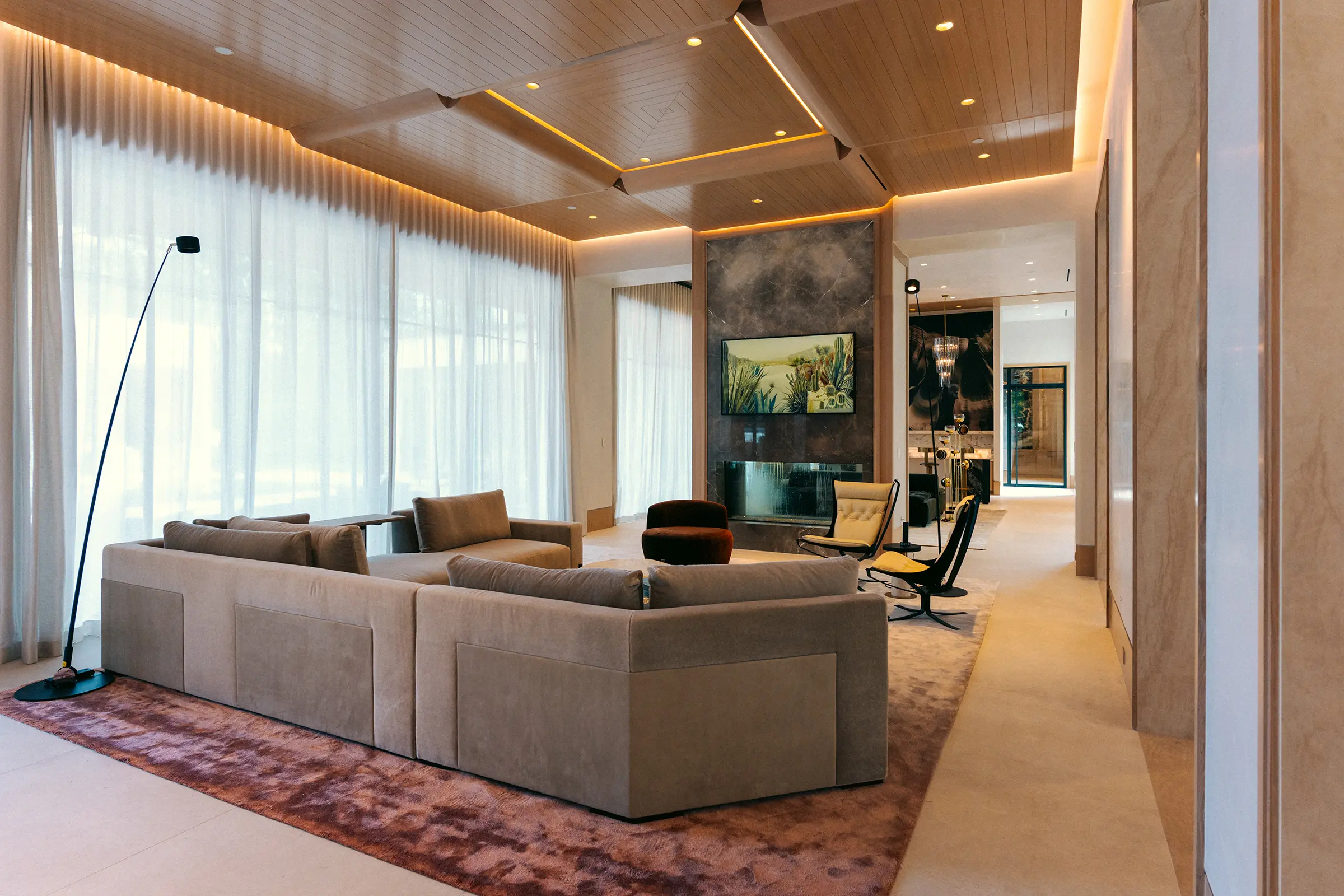 Living room with cove lighting, sheer drapery and a fireplace in a Houston home